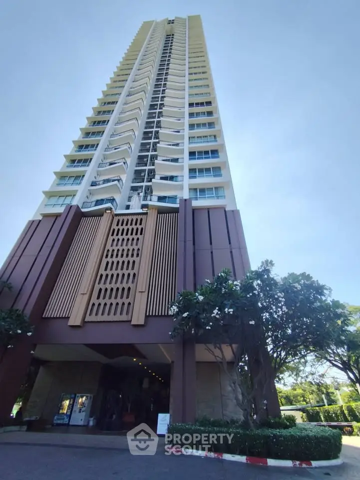 Stunning high-rise building with modern architecture and lush greenery at the entrance.