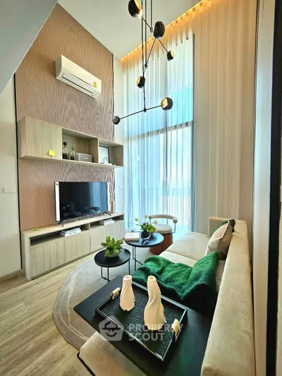 Modern living room with high ceiling, stylish lighting, and cozy seating area.
