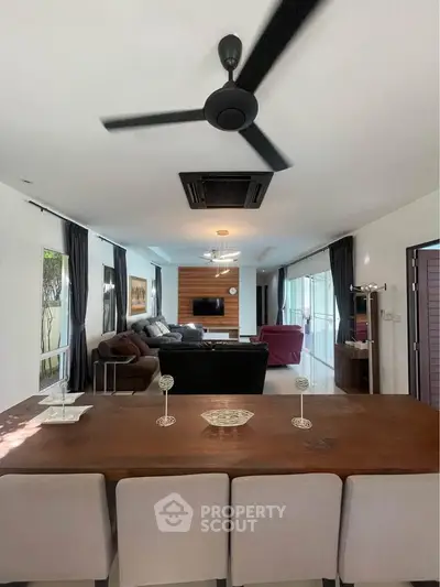 Spacious modern living room with stylish decor and ceiling fan, perfect for relaxation and entertainment.
