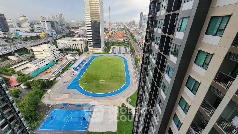 Stunning cityscape view from high-rise building overlooking sports field and urban skyline.