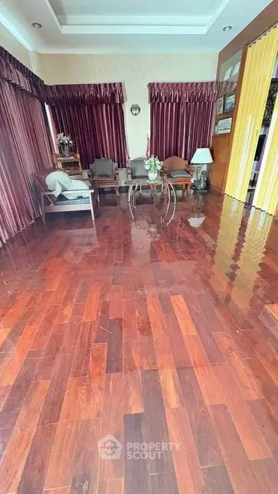 Spacious living room with polished wooden floors and elegant curtains.