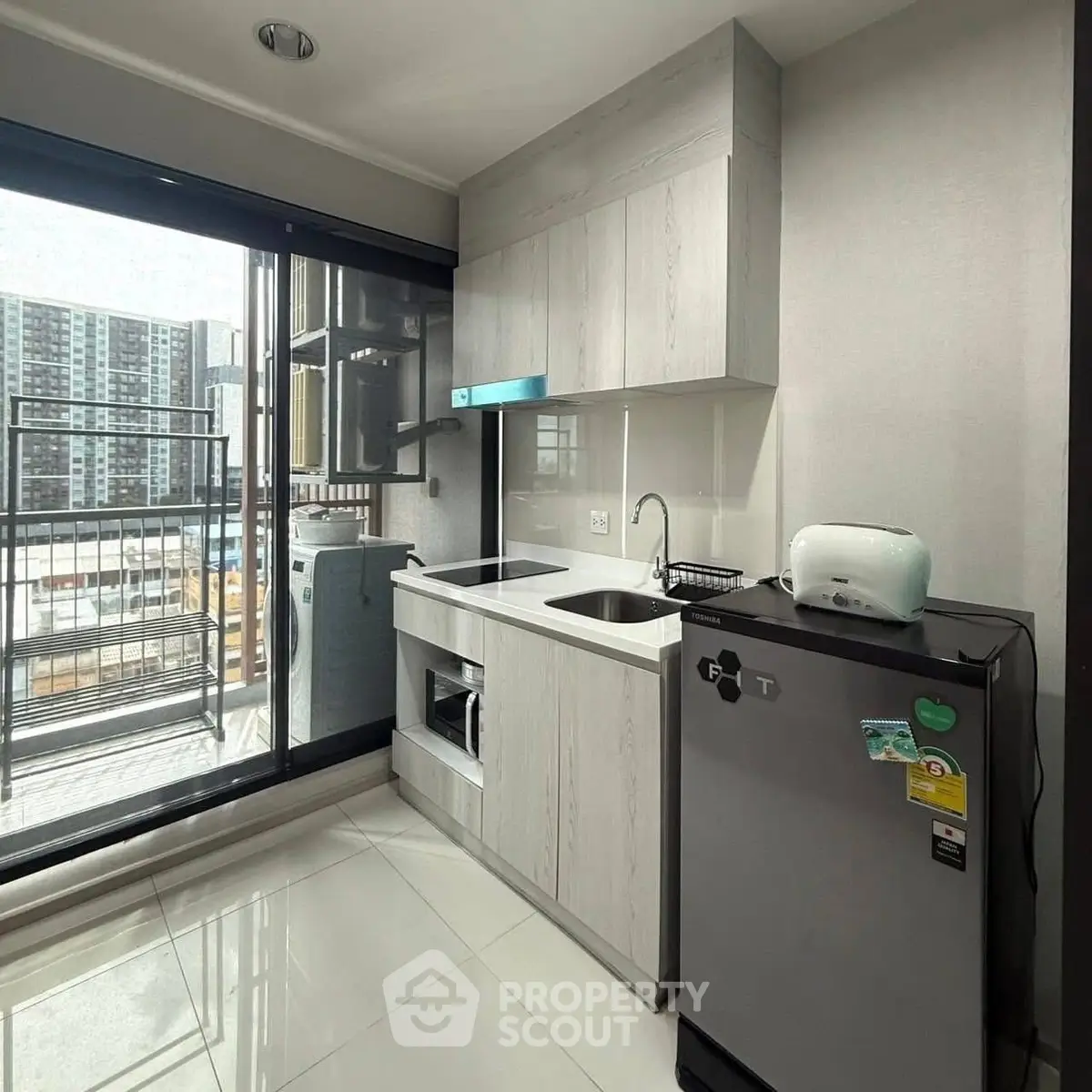 Modern kitchen with balcony view, featuring sleek cabinetry and compact appliances.