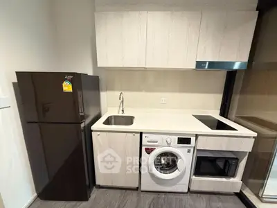 Modern kitchen with sleek appliances including fridge, washing machine, and microwave in compact layout.