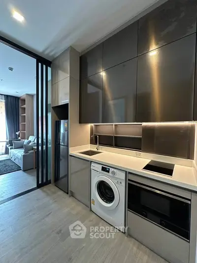 Modern kitchen with sleek cabinetry, built-in appliances, and open layout leading to living area.