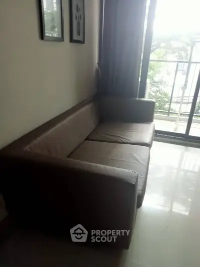 Cozy living room with modern sofa and balcony view, perfect for relaxation.
