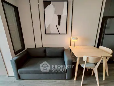 Modern living room with sleek sofa, stylish artwork, and cozy dining area.