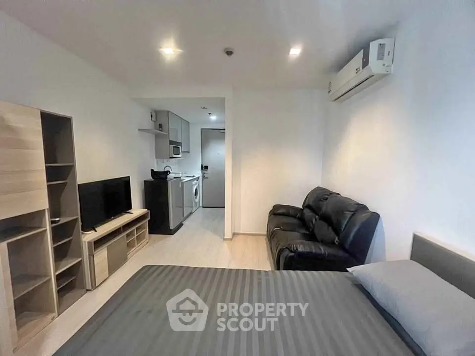 Modern studio apartment with sleek furnishings and air conditioning, featuring a cozy living area and compact kitchen.