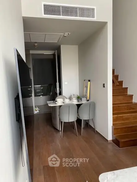 Modern dining area with sleek furniture and wooden staircase in stylish apartment