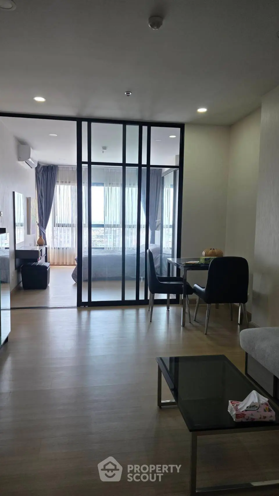 Modern open-plan living room with glass partition and city view