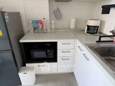 Modern kitchen with sleek white cabinets, microwave, and coffee maker