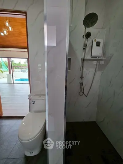 Modern bathroom with shower and toilet, pool view from window.