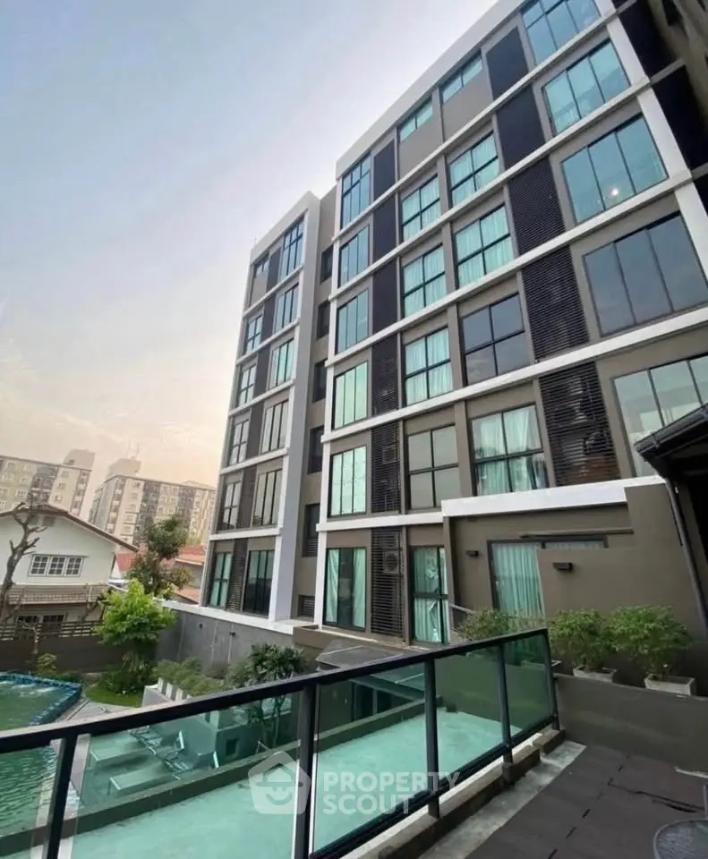 Modern apartment building with glass balconies and pool view