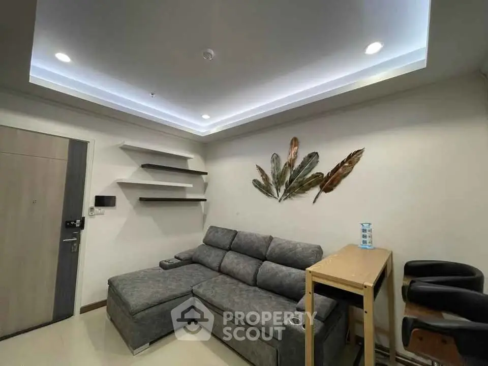 Modern living room with stylish gray sofa and decorative wall art, featuring sleek shelving and ambient lighting.