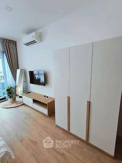 Modern bedroom with sleek furniture and large window offering natural light.