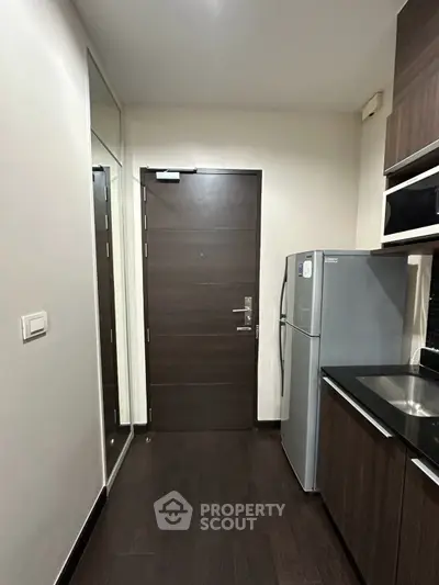 Modern kitchen entrance with sleek wooden door and stainless steel fridge