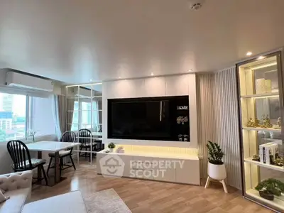 Modern living room with sleek design, large TV, and elegant dining area in a bright apartment.