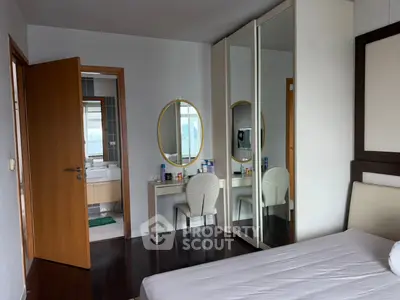 Modern bedroom with mirrored wardrobe and ensuite bathroom in stylish apartment.