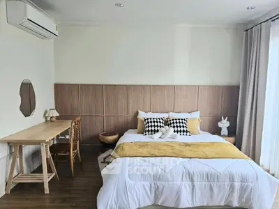 Spacious bedroom with modern decor and natural light, featuring a cozy bed and stylish workspace.