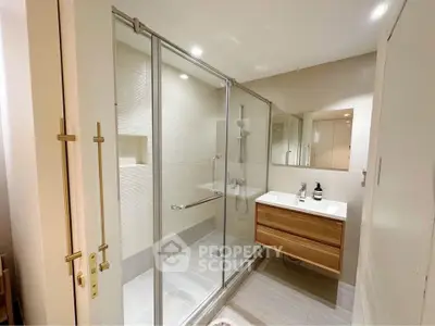 Modern bathroom with glass shower and sleek vanity in a contemporary home.