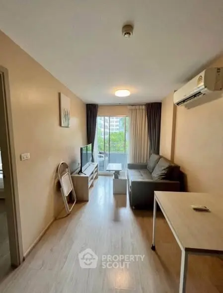 Cozy living room with modern decor and balcony view in urban apartment.