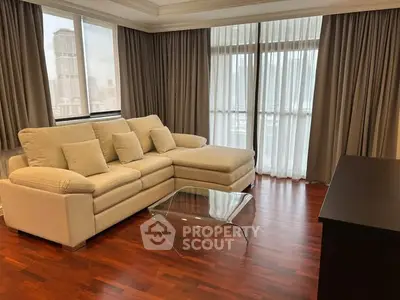 Spacious living room with elegant sofa and city view, featuring hardwood floors and large windows.