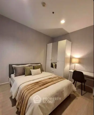 Cozy bedroom with modern decor, featuring a comfortable bed, stylish wardrobe, and a sleek desk with lamp.