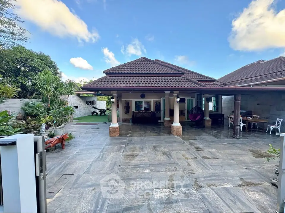 Spacious villa with tiled courtyard and lush greenery, perfect for luxury living.