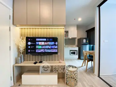 Modern living room with stylish TV setup and open kitchen layout in a cozy apartment.