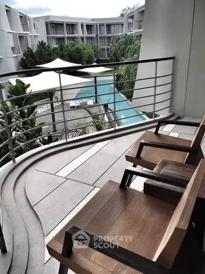 Luxurious balcony view overlooking a serene pool and lush greenery in a modern apartment complex.