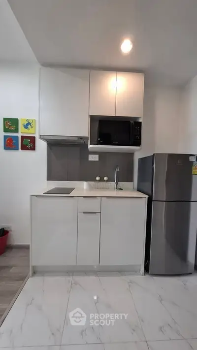 Modern compact kitchen with sleek appliances and colorful wall art