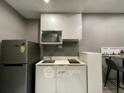 Modern compact kitchen with sleek white cabinets and stainless steel appliances