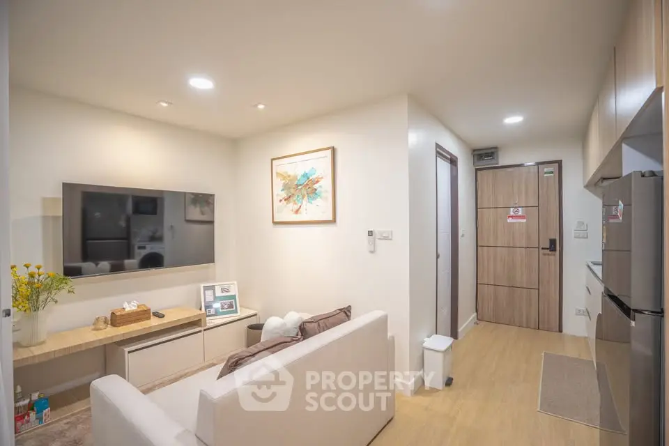 Modern living room with sleek design, featuring a cozy sofa, wall-mounted TV, and stylish decor in a compact space.
