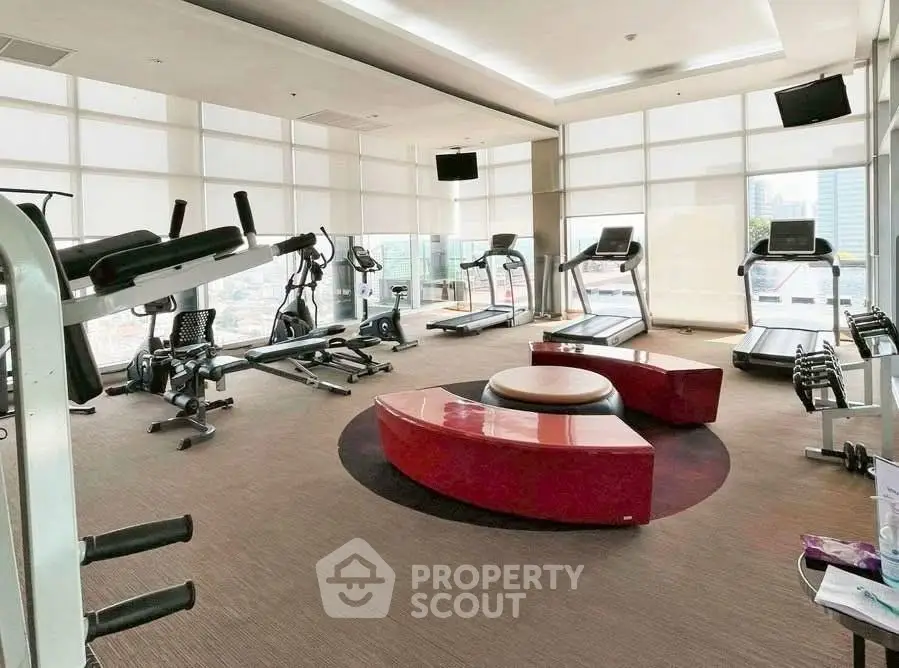 Spacious modern gym with city views and state-of-the-art equipment in luxury building.