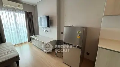 Modern living room with TV, fridge, and large window offering city view.