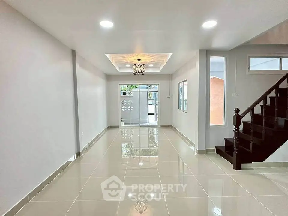 Spacious modern living room with glossy tile flooring and elegant staircase