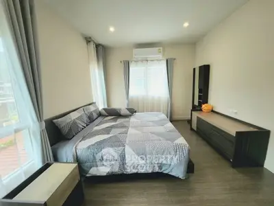 Spacious bedroom with modern decor and large windows for natural light.