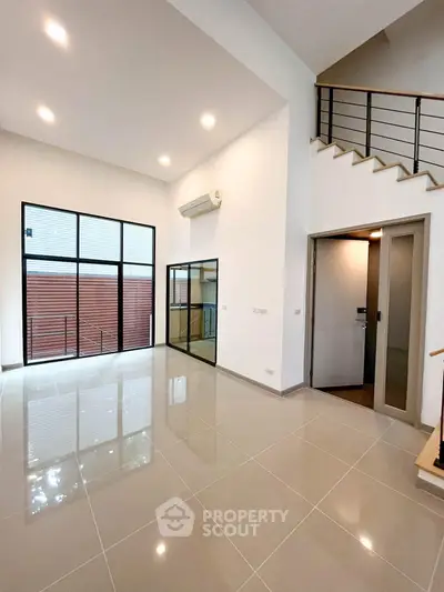 Spacious modern living room with high ceilings and large windows in a contemporary home.