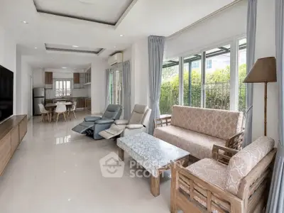 Spacious living room with modern furniture and large windows overlooking greenery.