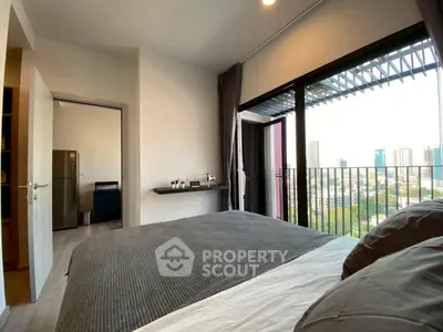 Modern bedroom with city view and balcony access in high-rise apartment.