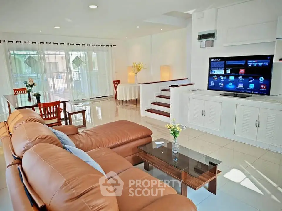 Spacious living room with modern decor and large TV, perfect for family gatherings.