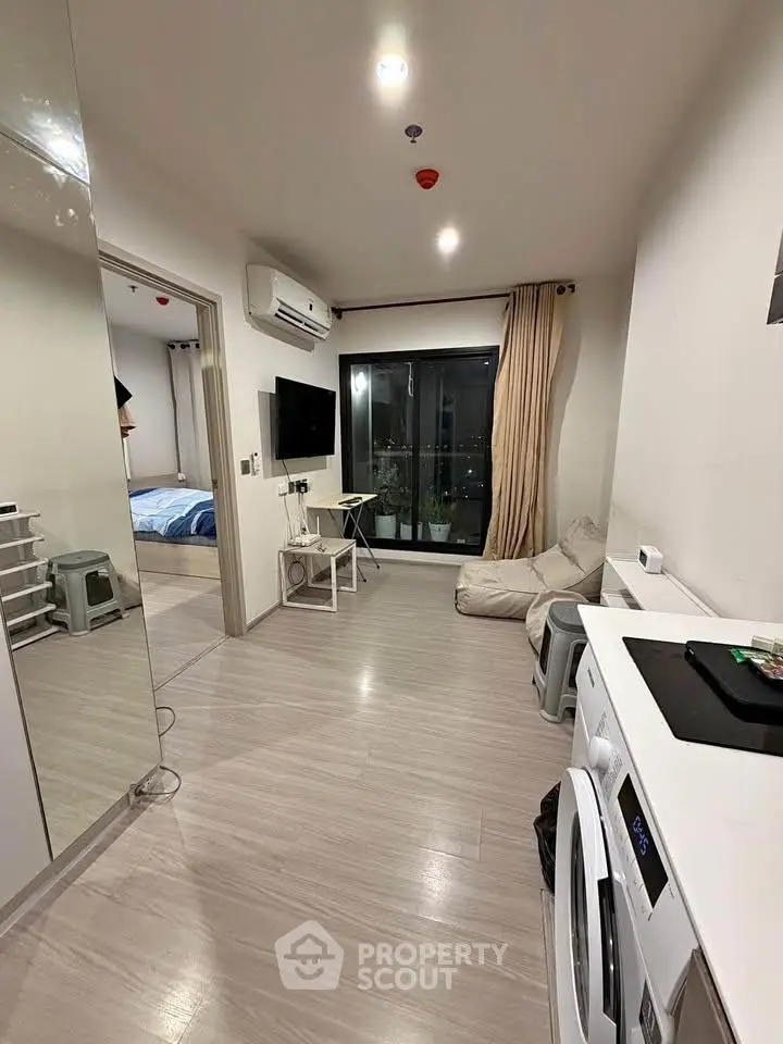 Modern apartment interior with open layout, featuring a cozy living area and bedroom view.