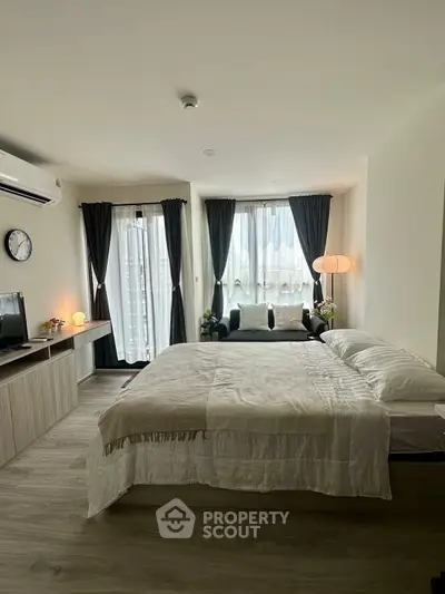 Modern bedroom with stylish decor, large windows, and cozy seating area in a contemporary apartment.