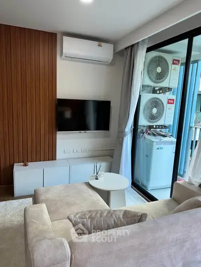 Modern living room with air conditioning and balcony view, featuring sleek furniture and natural light.