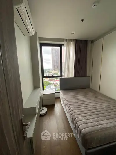 Cozy bedroom with city view, featuring modern furnishings and ample natural light.