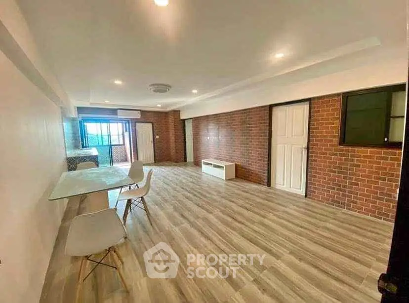 Spacious modern living room with brick accent wall and stylish flooring