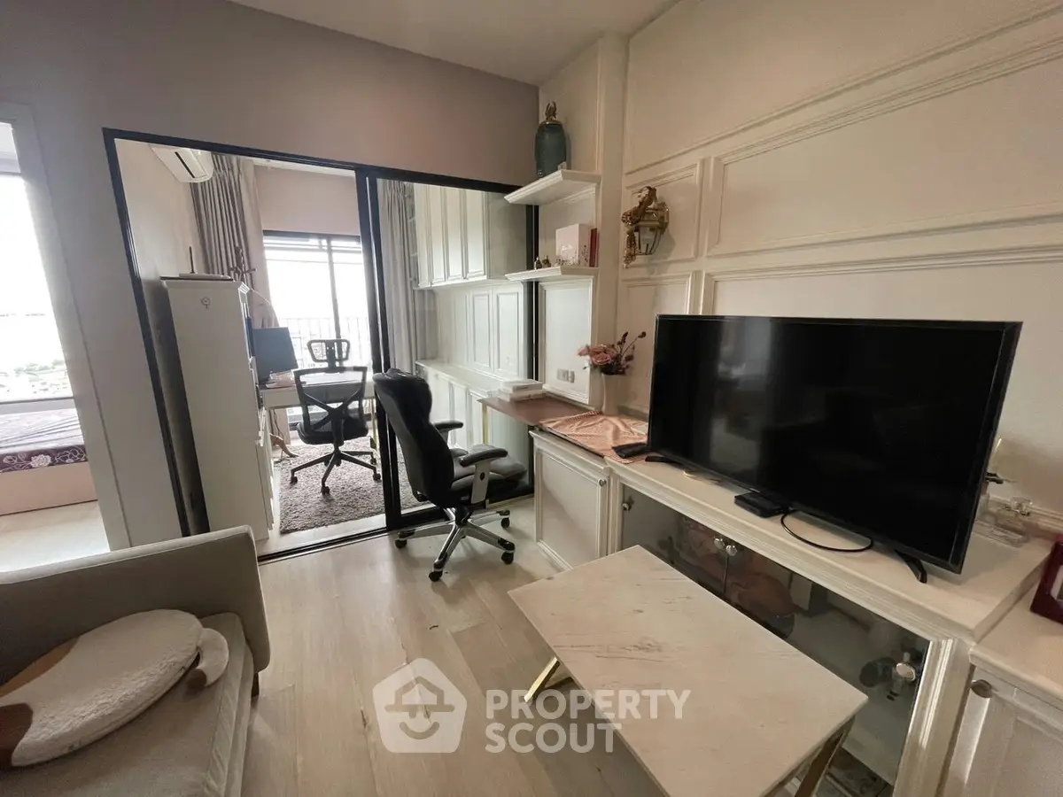 Modern living room with sleek TV setup and cozy workspace, perfect for urban living.