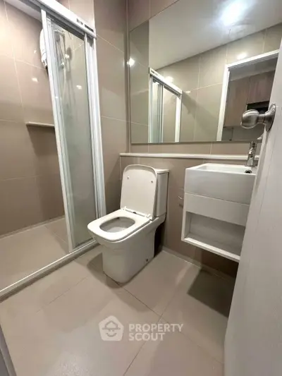 Modern bathroom with sleek shower and compact vanity in a stylish apartment.