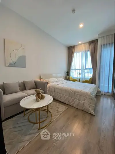 Cozy bedroom with modern decor and large windows offering natural light.