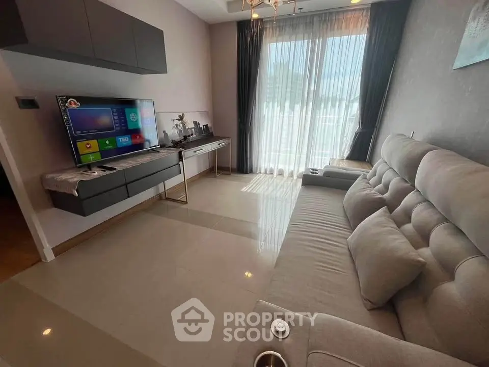 Modern living room with sleek furniture and large window offering natural light.