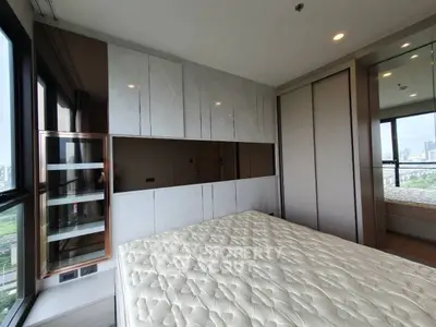 Modern bedroom with large windows and city view, featuring sleek built-in storage and a comfortable mattress.